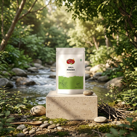 A stand-up pouch of Nature's Basket Amla Powder on a solid beige background. The packaging is white with a green lower section, featuring the brand logo and product name in black text.